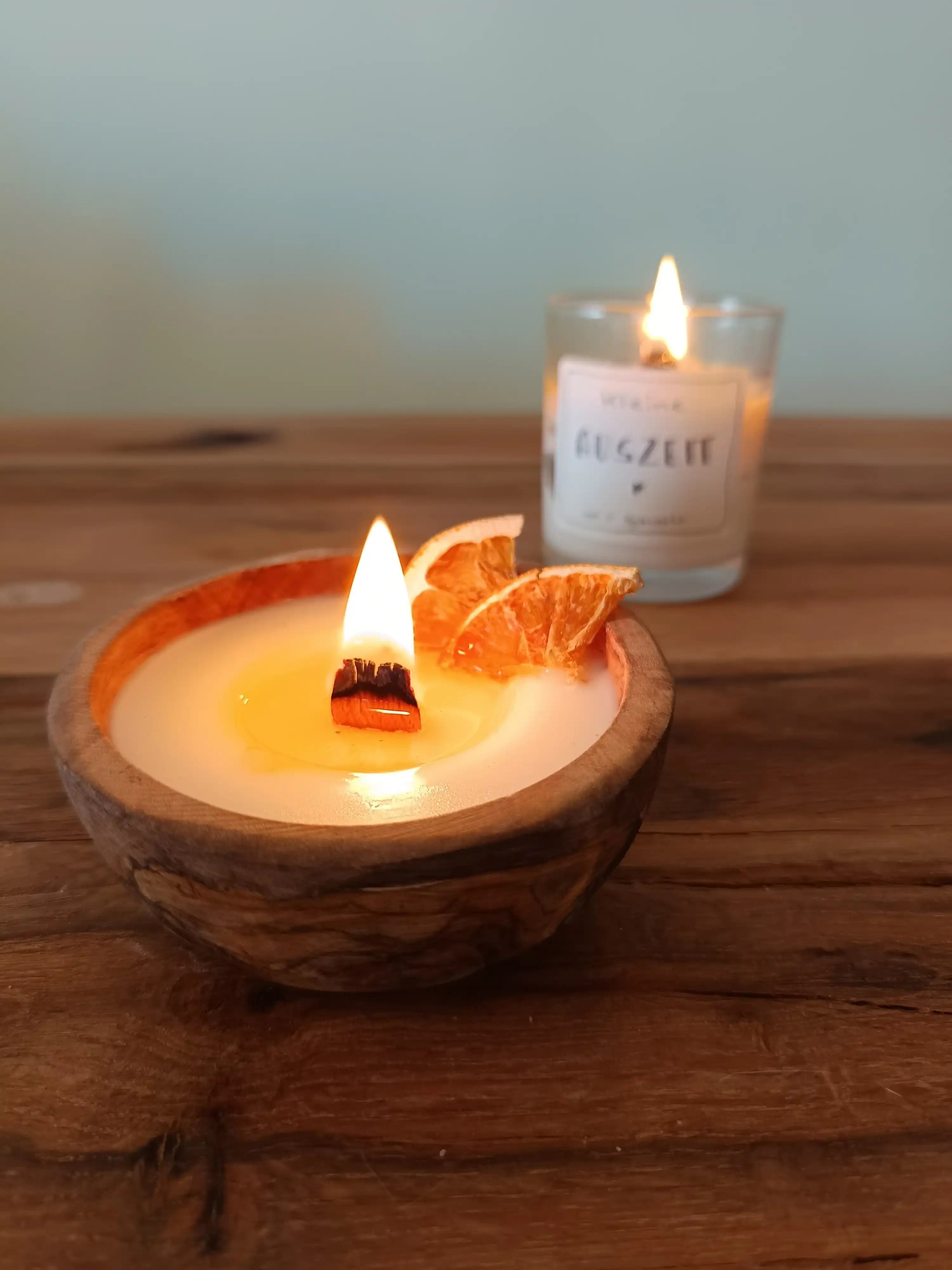 Handgefertigte Sojawachs-Kerze in Holzschale mit Orangenscheiben, brennend