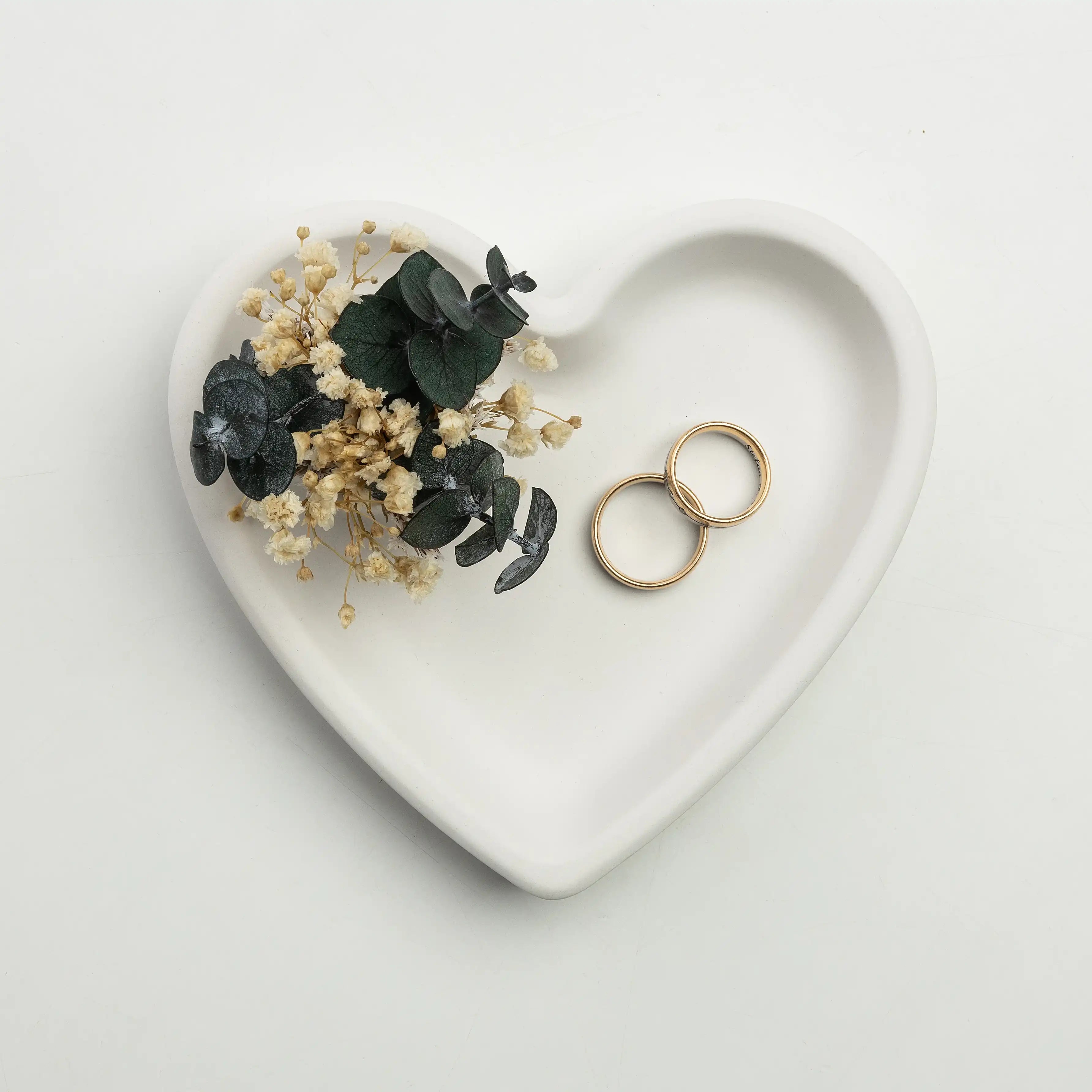 Herzförmige Keramikschale mit Trockenblumen und Eukalyptus, goldene Ringe