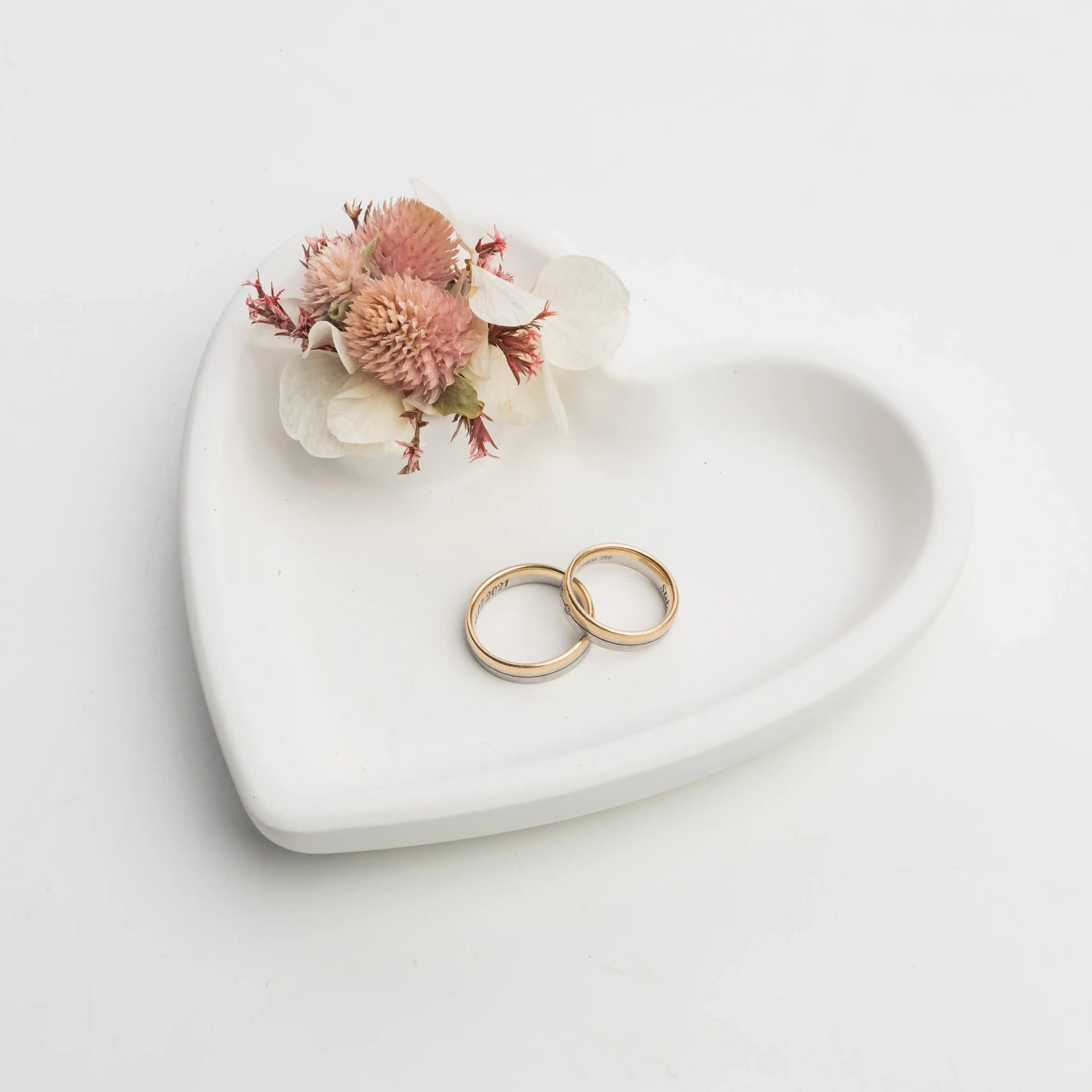 Personalisierte Hochzeitsringe mit Trockenblumen auf Herzschale