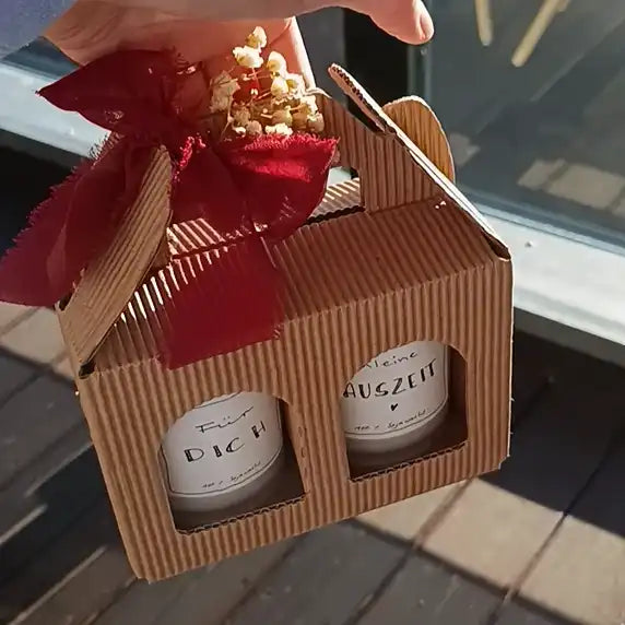 Handgefertigte Sojawachskerzen im Geschenkbox mit rotem Band und Trockenblumen